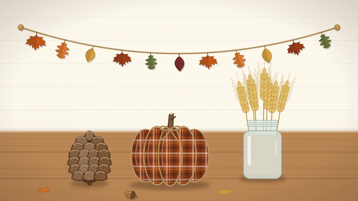 A small fabric pumpkin, a paper leaf garland, a jar of wheat stems and a pinecone grouped on a wooden tabletop