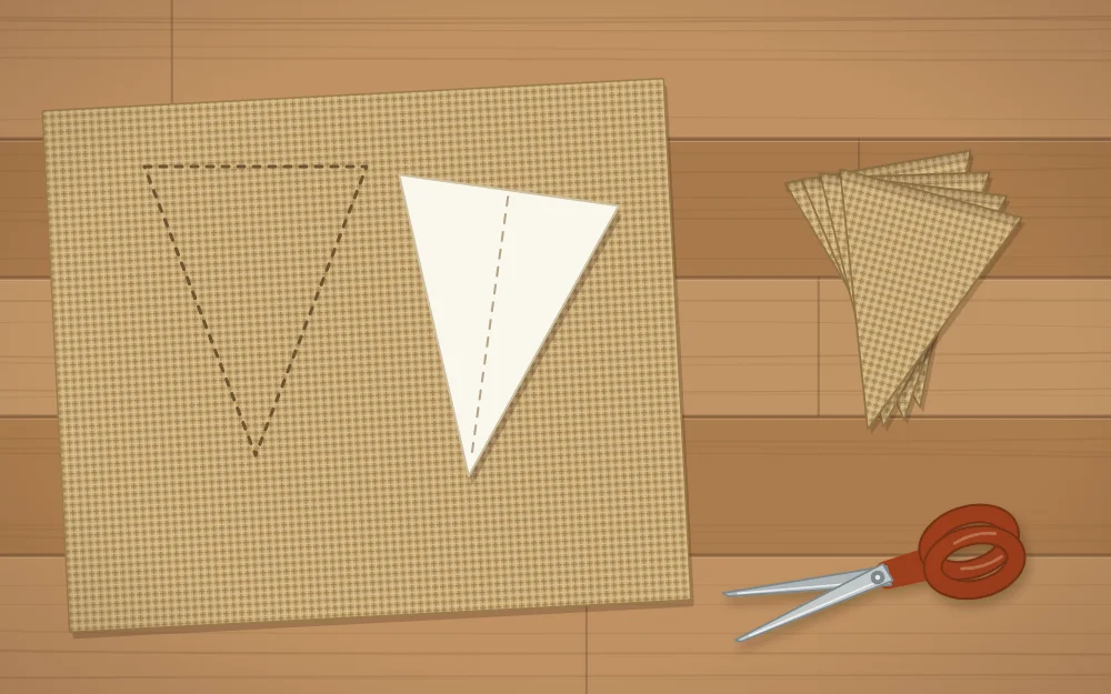 A paper pennant template lying on burlap with cut flags stacked beside it and scissors