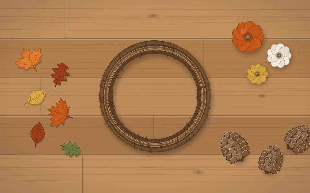 A bare grapevine wreath base on a table with groups of leaves, small pumpkins and pinecones laid out around it