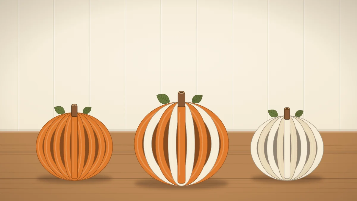 Three round pumpkins made from curved orange and cream paper strips with small green paper leaves and rolled brown stems